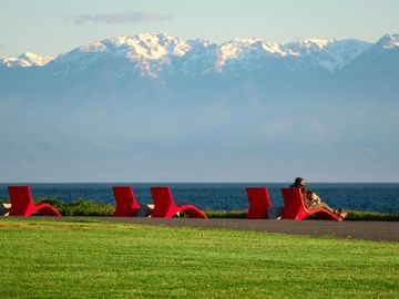 Red chairs at Clover Point facing the Olympic Mountains across the strait